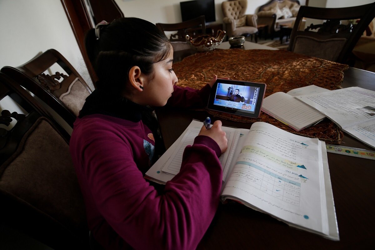 Tecrit altındaki Gazzeli bir öğrenci, derslerinden geri kalmamak için tablet üzerinden çalışırken görülüyor.