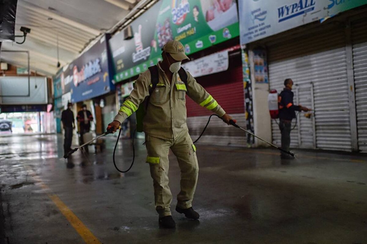 Meksika- Temizlik personeli, 24 Mart'ta Mexico City'nin en büyük gıda tedarik merkezi olan Central de Abasto toptan satış pazarında dezenfektan püskürtüyor.  