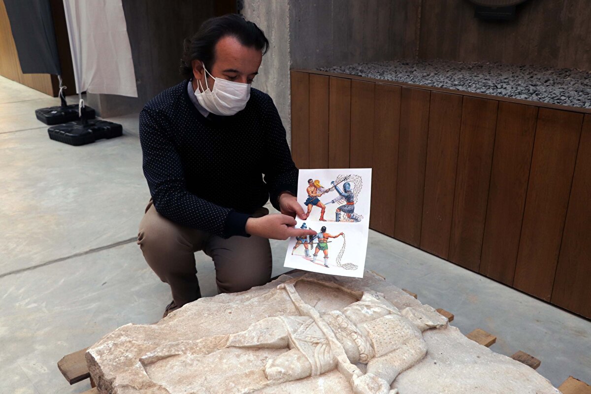 "Bizim rölyefimizin üzerindeki gladyatörde bir ağ ya da mızrak yok. Retiarius denilen gladyatörlerde 'manica' denilen ve kalbini koruyan sol koluna kadar uzanan bir zırh vardır. Çünkü hareket kolu sol koludur. Sol kolu rakibine en yakın yerdir. Kalbini ve vücudunun sol kısmını korumak için giyer."