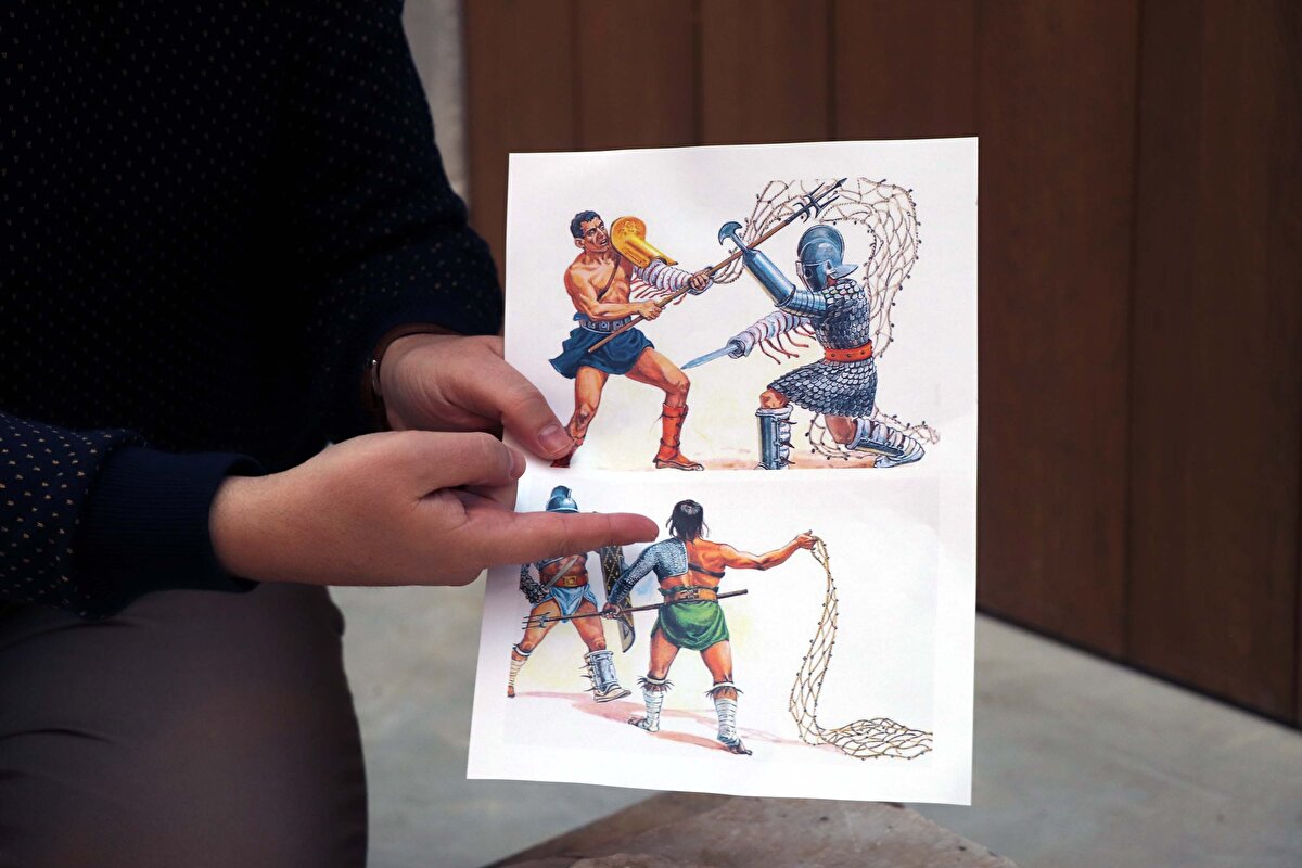 "Gladyatörler arasında manicayı sol koluna takan tek gladyatör bu. Diğer gladyatörler sağ koluna takar. Balteus denilen bir kemer vardır. Ağı kullandığı zaman, sağ elinde tuttuğu ağın bir ucunu kemerine bağlar. Aynı zamanda 'subligaculum' olarak da adlandırılan iç çamaşırı diyebileceğimiz belinde bir kıyafeti vardır. Bu rölyefimizdeki gladyatörün kafası kırık. Retiarius sınıfı gladyatörler kask takmazlar. Kafaları çıplaktır. Bacaklarında ekstra bir koruma yer almaz."