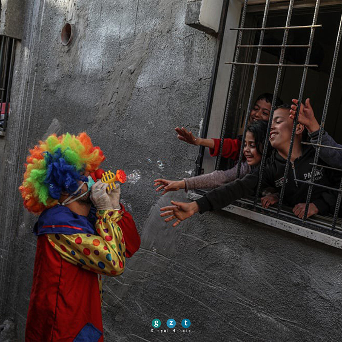 Filistinli bir palyaço, evlerinde oturmaktan sıkılan çocukları maskesiyle sokak sokak gezerek eğlendiriyor. (Mohammed Saber/EPA)