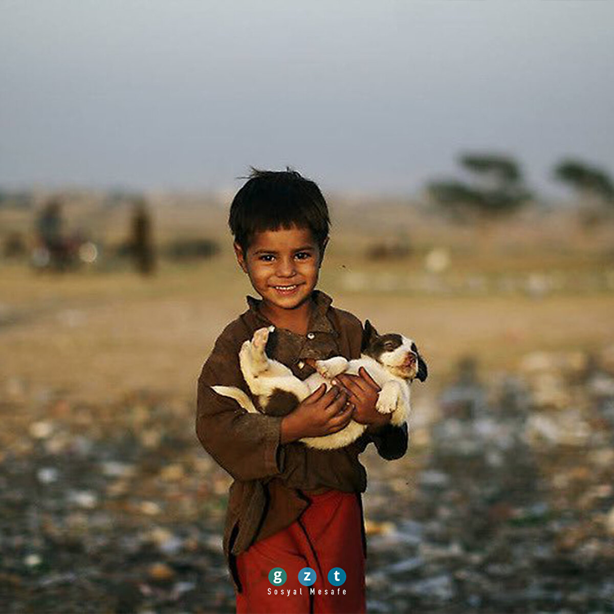 Pakistan'da bir mülteci çocuk, çöp yığınında bulduğu köpeği taşıyor (Muhammed Muheisen)