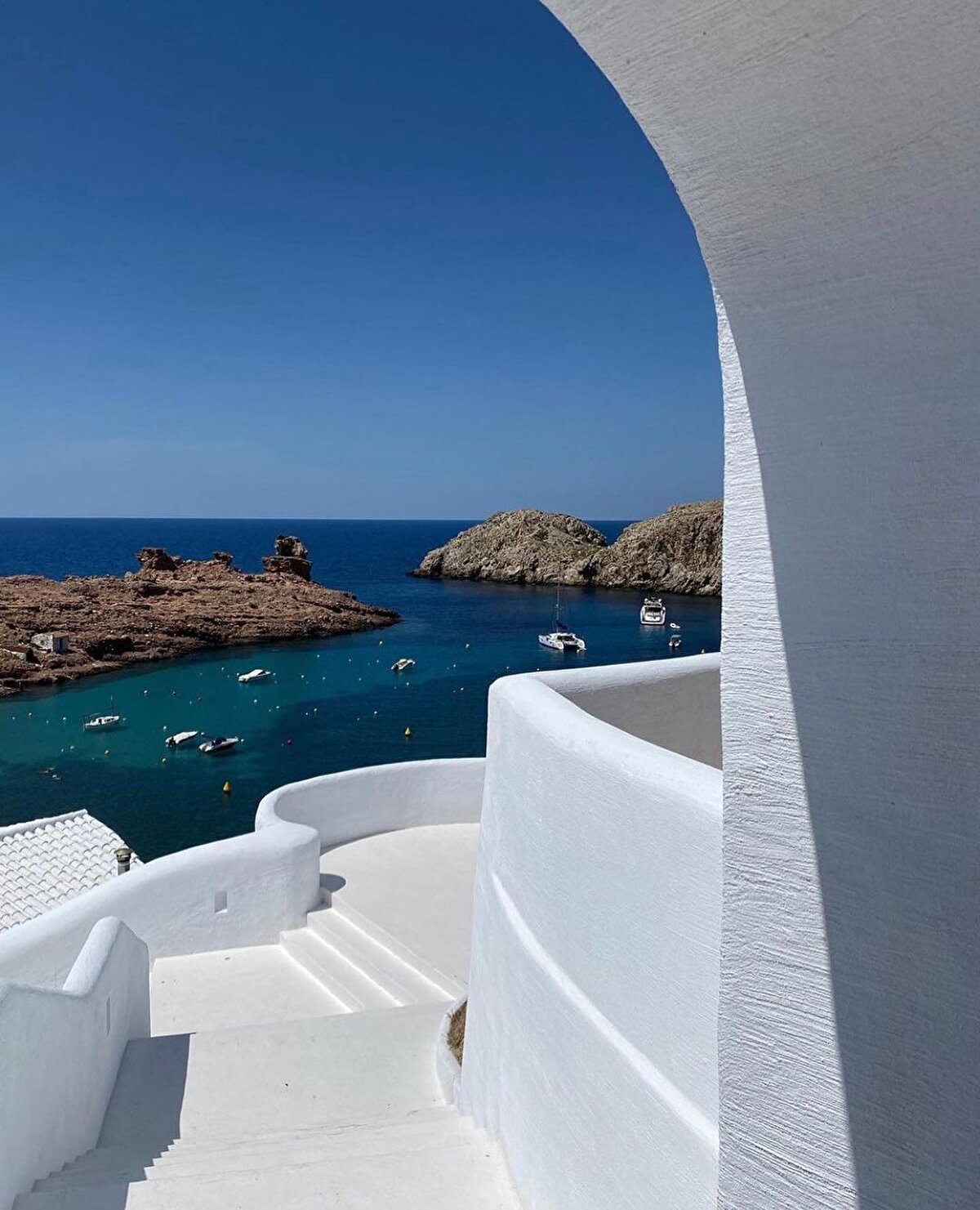 ✨ Adanın içine doğru sokulan halicin iki yanından, farklı egemenliklerin izlerini taşıyan yapıları izlemek her zaman yaşayamayacağınız bir keyif. Seyir teraslarıyla birbirine nazire yapan basamaklı evler, taraçalar… Sanki yeni bir savaşı beklermiş gibi namlularını açık denize doğru doğrultmuş toplar, iki kıyısında güzellikte birbiriyle yarışan bağlı tekneler, bir Akdeniz tembelliğinde henüz kepenklerini kaldırmamış dükkânlar, tek tük araç geçen sakin sahil yollarıyla Mahon, Minorca'nın başkentliğini Cituadella’nın elinden kaptığını çok iyi anlatıyor.⠀