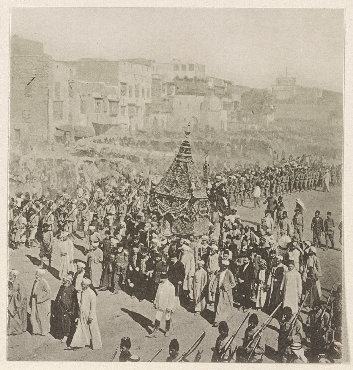 Manakha Meydanı boyunca surre alayı, 1914. Surre; Arapça para kesesi anlamına gelir ve bir kervan vasıtasıyla Mekke-Medine’ye değerli hediyeler göndermeyi ifade eder. Surrede çeşitli hediyelerin yanı sıra, Efendimiz'i (s.a.v) ve ailesini temsilen bir mahmil de bulunurdu.