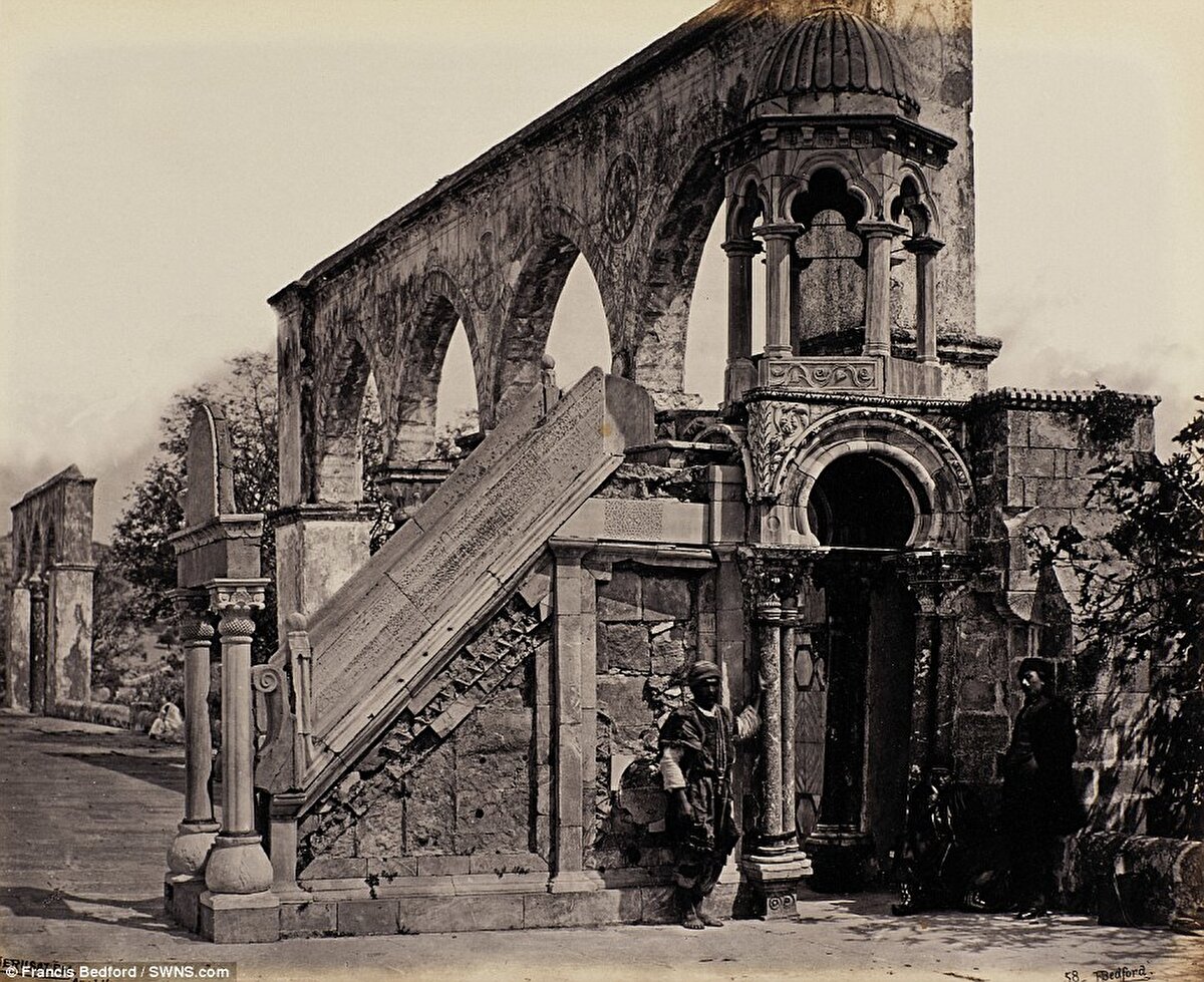 Fotoğrafta görülen Kadı Burhaneddin Minberi, Kubbetü’s Sahra’nın avlusunda, Kıble Mescidi’ne giden güney kemerlerin batı bölümünde yer alır. 1309 yılında Başkadı Burhaneddin Cemaâ tarafından inşa ettirilmiştir. İlk yapıldığı dönemlerde ahşaptan ve tekerlekli bir şekilde yapılırken, daha sonraları mermerden ve taştan inşa edilmiş ve hareketsiz bir yapı halini almıştır. Minberin üzerinde “Mizan Kubbesi” diye isimlendirilen küçük ve güzel bir kubbe bulunur. Kadı Burhaneddin Minberi Mescid-i Aksâ içerisinde açık alanda bulunan tek minber olma özelliği taşımaktadır.