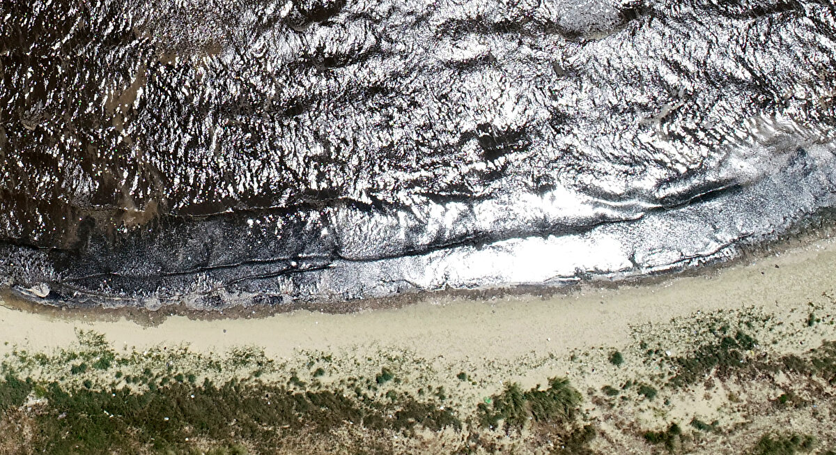Balıkesir'in sahillerinde kumun rengi, kirlilik ve müsailaj nedeniyle sarıdan siyaha döndü. Sahillerdeki kirlilik, dron ile havadan görüntülenirken, Bandırma Kent Konseyi Başkanı Dr. Murat Ergöz, soruna acil çözüm bulunması gerektiğini söyledi.