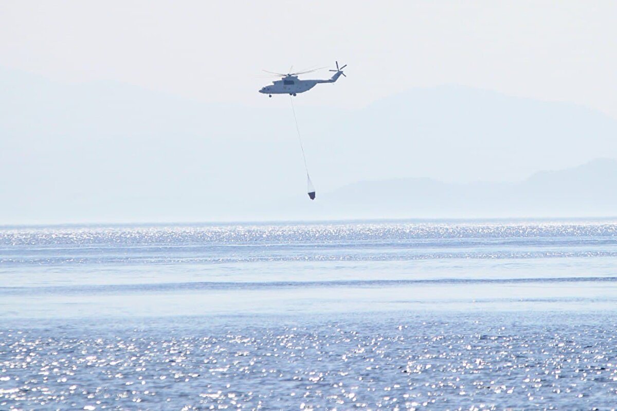 Ekipler, zaman zaman sert esen rüzgar nedeniyle kuvvetlenen yangını kontrol altına almak için mücadeleyi sürdürüyor.