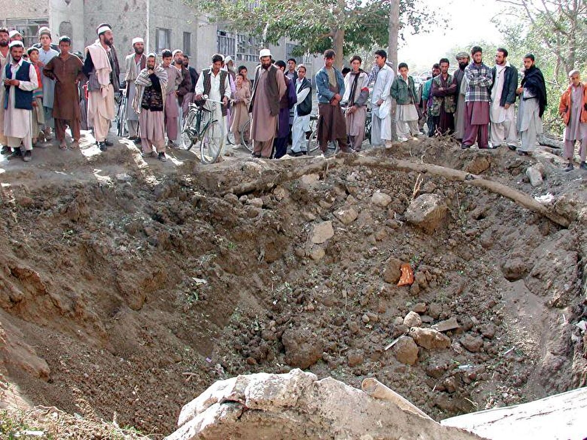  Kabil'de, ABD’nin hava saldırıları sırasında atılan bir bombanın neden olduğu çukuru inceleyen Afganlar. 18 Ekim, 2001.