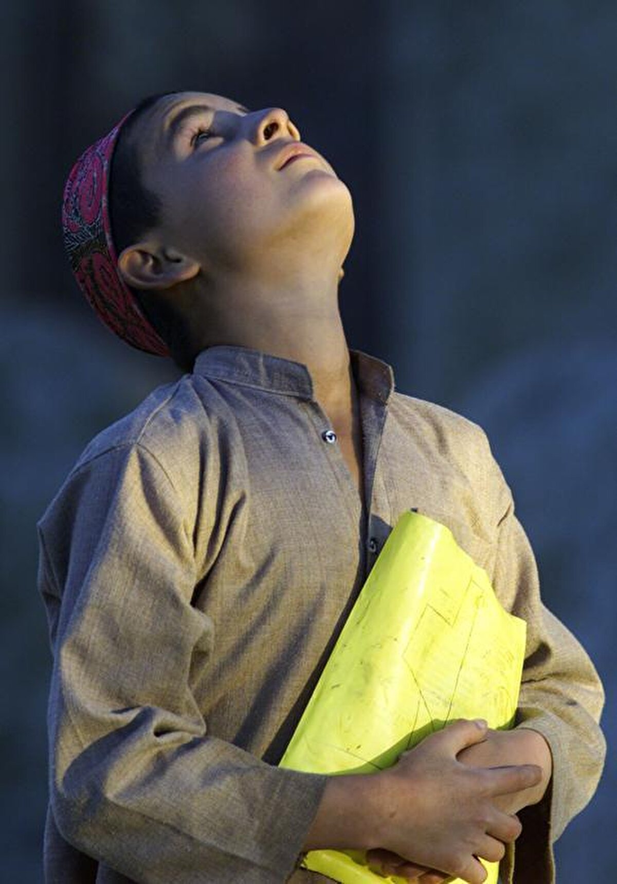 3 Kasım 2001'de ABD savaş uçakları Kuzey Afganistan'daki Taliban mevzilerini bombalarken elinde ABD’nin dağıttığı gıda yardım paketinden yapılmış bir çanta tutan Afgan çocuk, gökyüzüne bakarken görülüyor.