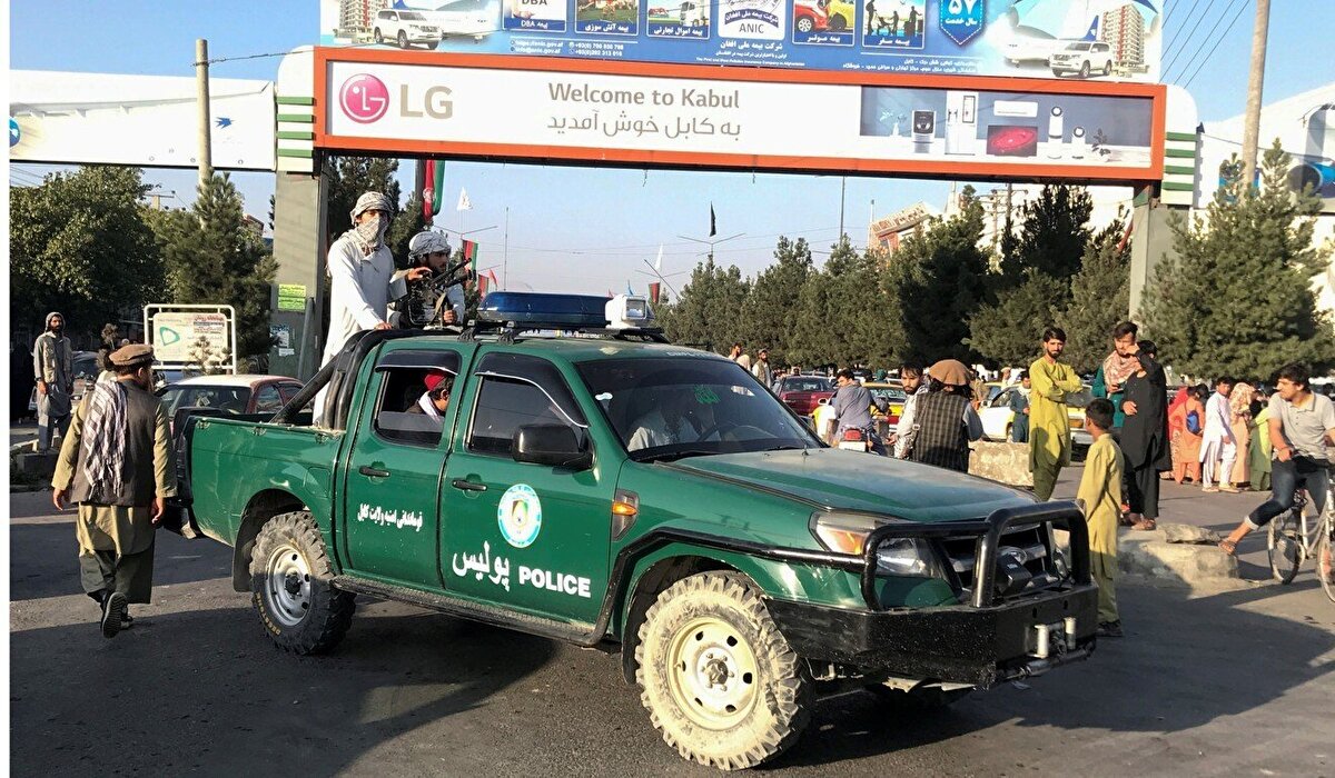 Afganistan'ın başkenti Kabil'deki Hamid Karzai Uluslararası Havalimanı'nın dışında “Kabil’e hoş geldiniz” tabelasının altında Taliban militanları. 16 Ağustos, 2021.