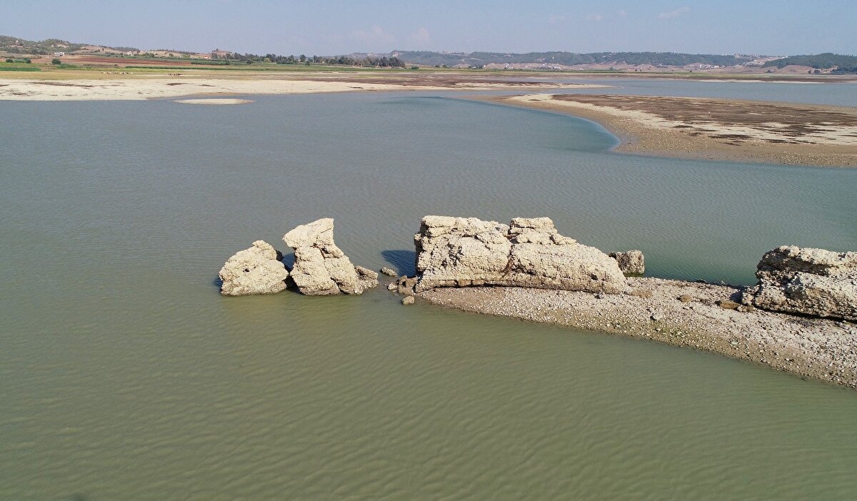 “Seyhan Barajı'nın göllenmiş olduğu sahada kalan ve bazı mütehassıs seyyahlarca Augusta Antik şehri olduğu beyan edilen örenin tetkikini, Maarif Vekaleti Eski Eserler ve Müzeler Umum Müdürlüğü bize havale etmişti. Sahaya suyun koyuverilmesinden 10 gün kadar evvel, yani 5-15 9 1955 tarihleri arasında mahallinde bir inceleme yaptık. Bu ören Adana şehrinden 25 kilometre doğuda ve Seyhan Nehri'nin şimale uzanan kollarından biriyle, Kuruçay Vadisi'nin birleştiği kısımda ve çayın hasıl ettiği terasanın yarımada şekline girmiş bir düzlüğünde bulunmakta idi. Bugün bunlardan Karaömerli köyünün bir kısmı gölün kenarında kalmıştır, Gübe köyü ise (Antik kentin bulunduğu bölge) sular altındadır.