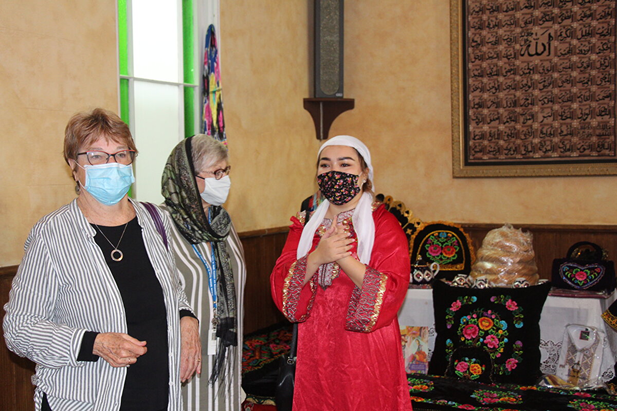 Kültürel kıyafetleriyle Uygur bir kadın ve açılışa katılan Kanadalı kadınlar...