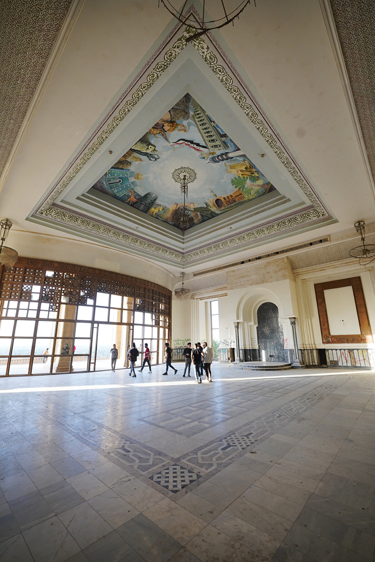 Bir zamanlar Saddam Hüseyin'in en zengin saraylarından biri olan yapının içinde, zarifçe oyulmuş mantolar ve kapılar, giriş holünde hâlâ asılı olan büyük avize dikkat çekiyor.