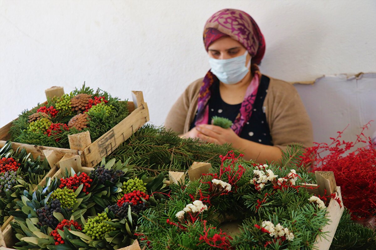 Orman Genel Müdürlüğü'nün izin ve desteğiyle biyolojik çeşitliliğin ön plana çıktığı Kocaaliler kırsalındaki ormanlardan toplanan kozalak, dal ve bazı meyvelerden çelenk şeklinde kapı süsü yapan kadınlar, hane ve ülke ekonomisine katkı sağlıyor.<br><br>