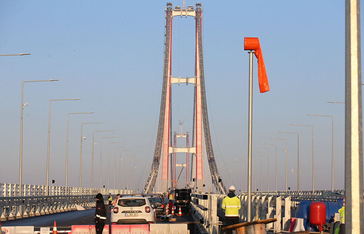 Tabliye boya ve rüzgar bariyerlerinin montaj çalışmaları da devam ediyor.<br><br>318 metre yüksekliğindeki çelik kulelerin üzerine yerleştirilecek 16 metre uzunluğundaki, Seyit Onbaşı'nın Çanakkale Savaşları'nda namluya sürdüğü top mermisini temsil eden mermi figürü Çimtaş firması tarafından Gemlik fabrikalarında hazırlanıyor.<br><br>1915 Çanakkale Köprüsü hariç olmak üzere otoyol kesimi ve yaklaşım viyadüklerinin tamamı aşınma (BSK) seviyesinde tamamlanırken, asma köprüdeki üst yapı imalatları gerçekleştiriliyor.
