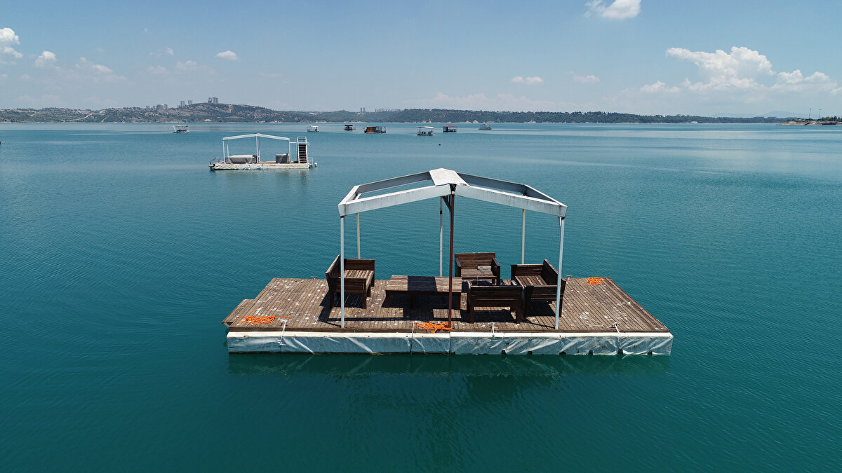 Adana’da, Seyhan Baraj Gölü’nde dubalar üzerine inşa edilen yüzen barakalar, günlüğü 700 liraya kiralanıyor. Barakalar dronla havadan görüntülenirken, yetkililer izinsiz yapıların kaldırılması için çalışma başlattı.<br>