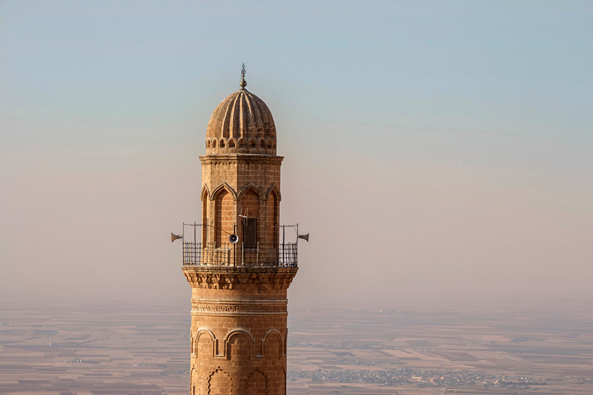  Kapılarımızı içeriden dışarıya doğru aralayacak olursak da avluda bizi bir Artuklu çeşmesi selamlıyor. Bu çeşmeyi de diğerlerinden farklı kılan noktası yaşamı simgeliyor olması. Su, kaynağından çıkarak insanın önce çocukluk ve sonra yetişkinlik dönemlerini sembolize eden küçük havuzlara doluyor. Ardından ölümü temsilen son havuzdan süzülerek yatağını bulup toprağa karışıyor. 