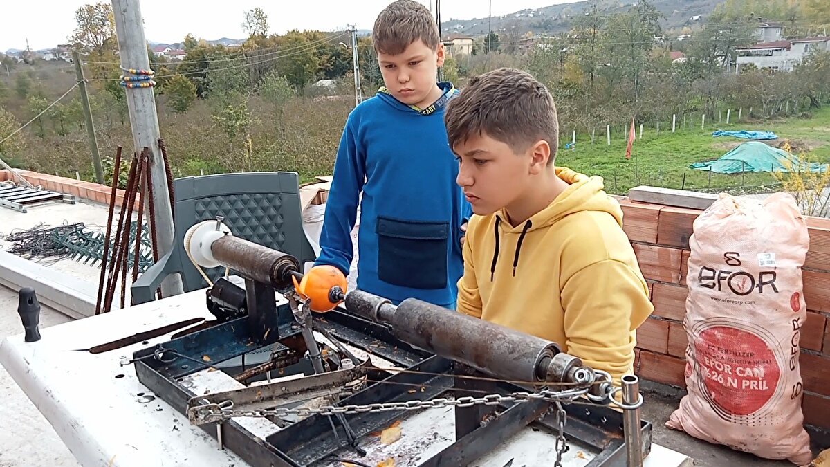 Muhammet Mert Gödek, AA muhabirine, makinenin çalışma prensibinin, demir kollarla sabitlenen meyvenin, dikiş makinesinden çıkma küçük motor yardımıyla döndürülmesi ve kabuğunun yan taraftaki kesiciyle soyulmasına dayandığını söyledi.<br><br>Kabuğu soyulan meyvenin boru yardımıyla kovaya düştüğünü belirten Gödek, "Biz ailecek birkaç seneden beri Trabzon hurması kurusu üretiyoruz. Ailemin zahmet çektiğini gördüm. Soyma işlemi uzun sürüyordu. Bunu bir makine ile yapabileceğim fikrini babama söyledim, çok yardımcı oldu. Kardeşimle birlikte böyle bir çalışma yaptık. Tabii ben bunu tek başıma yapamazdım. Fikrimi dinlediği için aileme teşekkür ederim." diye konuştu.