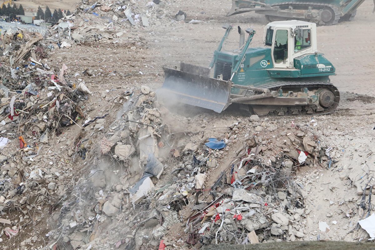 BİR NEVİ, ŞEHRİ BURAYA TAŞIYORUZ'<br>Depremin ardından çöken binalardan kalan enkazı taşıdıklarını, bunun ağır bir görev olduğunu ifade eden Doğru, "Bir nevi, şehri buraya taşıyoruz. Kolay bir görev değil. Bizim amacımız; şehirdeki depremin izlerini bir an önce silmek. Çalışmalarımız bu yönde devam ediyor. Öncelikle yoğun olarak ana caddelerden bu işleme başladık. Yaklaşık 1-1,5 ay içerisinde bu enkazın tamamını buraya getirmiş olacağız. Şu ana kadar yaklaşık 200-220 bin ton civarında malzemenin buraya naklini gerçekleştirdik. Arama-kurtarma çalışmalarının tamamlanmasını bekledik. Akabinde enkaz taşıma görevi bize verildi. Biz de bu minvalde çalışmalara devam ediyoruz" diye konuştu.