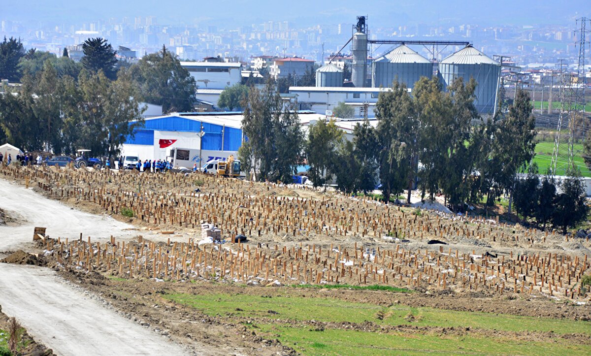 Antakya'da oluşturulan büyük deprem mezarlığında yüzlerce kişinin defni yapılırken, bazı mezar sahipleri de numaralı tahtaların üzerine tülbent bağladı.