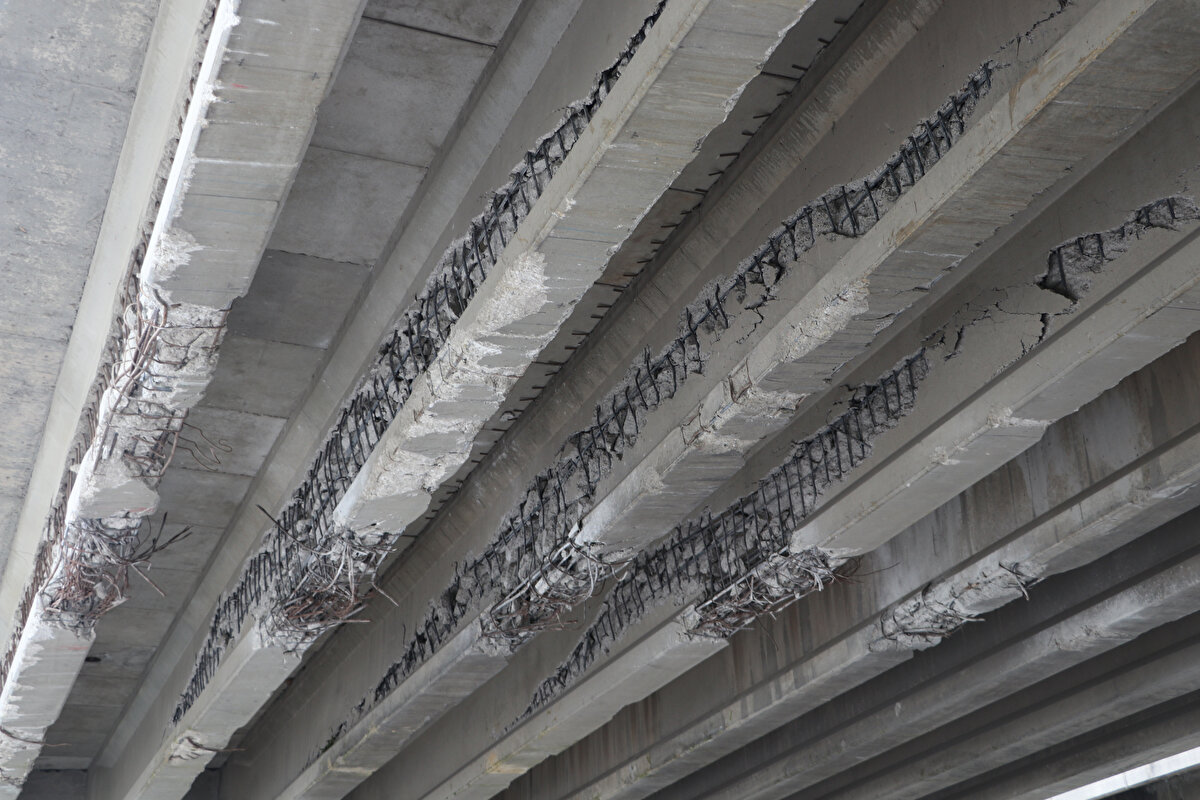 Köprü kirişlerinin betonundan ayrılmış açıkta görülen demirleri, kopan kabloları ve dökülen beton parçaları korkutan bir görüntü sergiliyor.