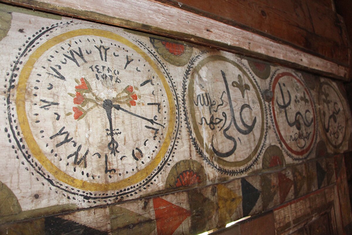 Cami duvarına saat çizmenin, insanın aklına en son gelecek şey olduğunu ifade eden Doç. Dr. Özkurt şunları söyledi:<br><br>“6’dan sonraki rakamlarda değişiklikler var. Acaba ‘Osmanlı Türkçesi rakamlar değil mi’ denecek kadar bir farklılık var. Bu da o saati üreten firmalar arasında farklı uygulamalar olabileceği gibi, o dönem Osmanlı ülkesine getirilen saatlerle büyük ölçüde benzerlikler gösteriyor. Nakkaşın, önemli bir alet olan zaman ölçeri yani saati tercih etmes, ciddi bir ayrıntı olarak durmaktadır. Detaylı bakıldığında 5’i 19 geçeyi gösteriyor. Saat detayı bizim geleneksel olarak bildiğimiz büyük camilerde de olan muvakkithane dediğimiz camilerin birimi olur. Orada muvakkit denen namaz vakitlerini belirleyen görevliler olurdu. İnsanlar muvakkitlerin belirlediği zamana göre ibadetlerini yapar ezanlar okunurdu. Ancak 1800’lere geldiğimizde yurt dışından gelen saatlerle birlikte daha dakik daha güvenli gibi bir durum var. Bu yüzden bugün inşa edeceğimiz bir camide süsleme anlayışı olarak akla gelecek en son şey saat iken, bir saat motifini camiye yapmak insanın aklına gelebilecek en son şey iken 1800’lerde dönemin şartları itibariyle saat önemli bir yer tutmakta.”