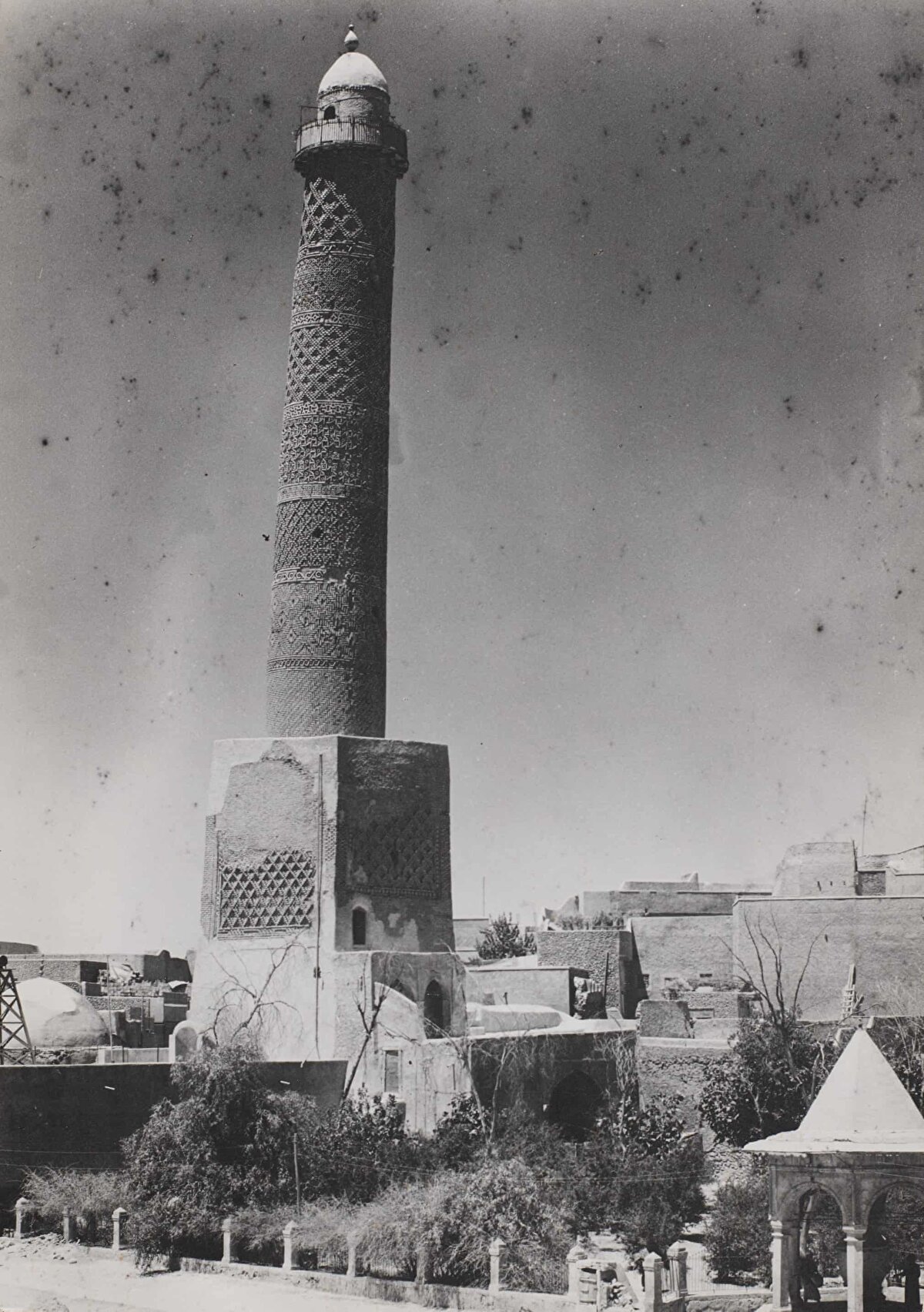 Musul Ulu Camii’nin (El-Nuri Ulu Camii) eğik minaresi, Ağustos 1944.<br><br>1173 yılında tamamlanan minare 45 metre idi. Adını Nureddîn Mahmud Zengî’den alan cami, eğik minaresiyle meşhurdu. Öyle ki, İbn Battuta 14. yüzyılda Musul'u ziyaret ettiğinde, minare zaten büyük ölçüde eğilmişti ve "el-Hadba" veya "kambur" takma adını almıştı. Eğimin nedeni tam olarak bilinmiyordu. Yerel geleneğe göre, vefat eden Hazret-i Muhammed’in göğe yükselirken bu bölgenin üzerinden geçmesiyle minare ona hürmeten eğilmişse de uzmanlar; bunun nedeninin kuzeybatıdan esen rüzgarlar, güneşin güney taraftaki tuğlalar üzerindeki etkisi veya tuğlaları bir arada tutmak için kullanılan zayıf alçıdan kaynaklandığına inanıyor.<br><br>Musul sakinleri camiyi kalabalık insan gruplarıyla çevreleyerek IŞİD'in vereceği zarara karşı defalarca korumuşsa da cami, Haziran 2017'de, Irak ve koalisyon güçleri caminin sadece 50 metre ilerisindeyken tamamen yıkılmıştır.