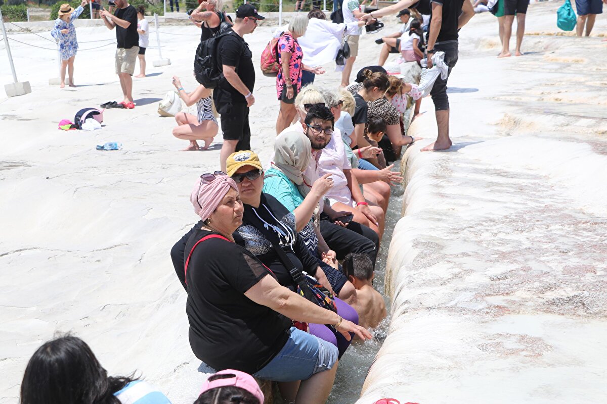 Gelen ziyaretçiler, beyaz travertenler üzerinde akan sıcak suda yalın ayak yürümenin keyfini yaşadı. Sıcak suyla temas eden çocuklar büyük keyif yaşarken, yetişkinler ise travertenler üzerinde bol bol hatıra fotoğrafı çektirdi. Pamukkale Ören Yeri'ne bugün saat 08.00'den bu yana, 6 bin 900 kişinin ziyaret ettiği öğrenilirken, ören yeri, saat 23.00'e kadar ücretsiz gezilebilecek.