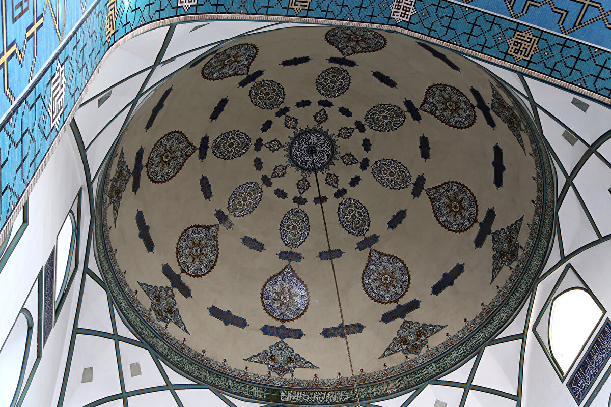 Caminin iç avlu duvarının hemen arkasında ise, Şiîlerin on iki imamının sekizincisi Ali er-Rızâ’nın türbesi yer alıyor. Caminin, İran’ın en önemli ziyaretgâhlarından olan bu kutsal kabul edilen İmam Rıza Türbesi’nin yanı başında yer alması, büyük bir ilgi ve alakaya sebebiyet vermiş. Öyle ki, eskiden farklı mekânlar olarak imar edilen türbe ve cami etrafında zamanla geniş bir külliye teşekkül etmiş.