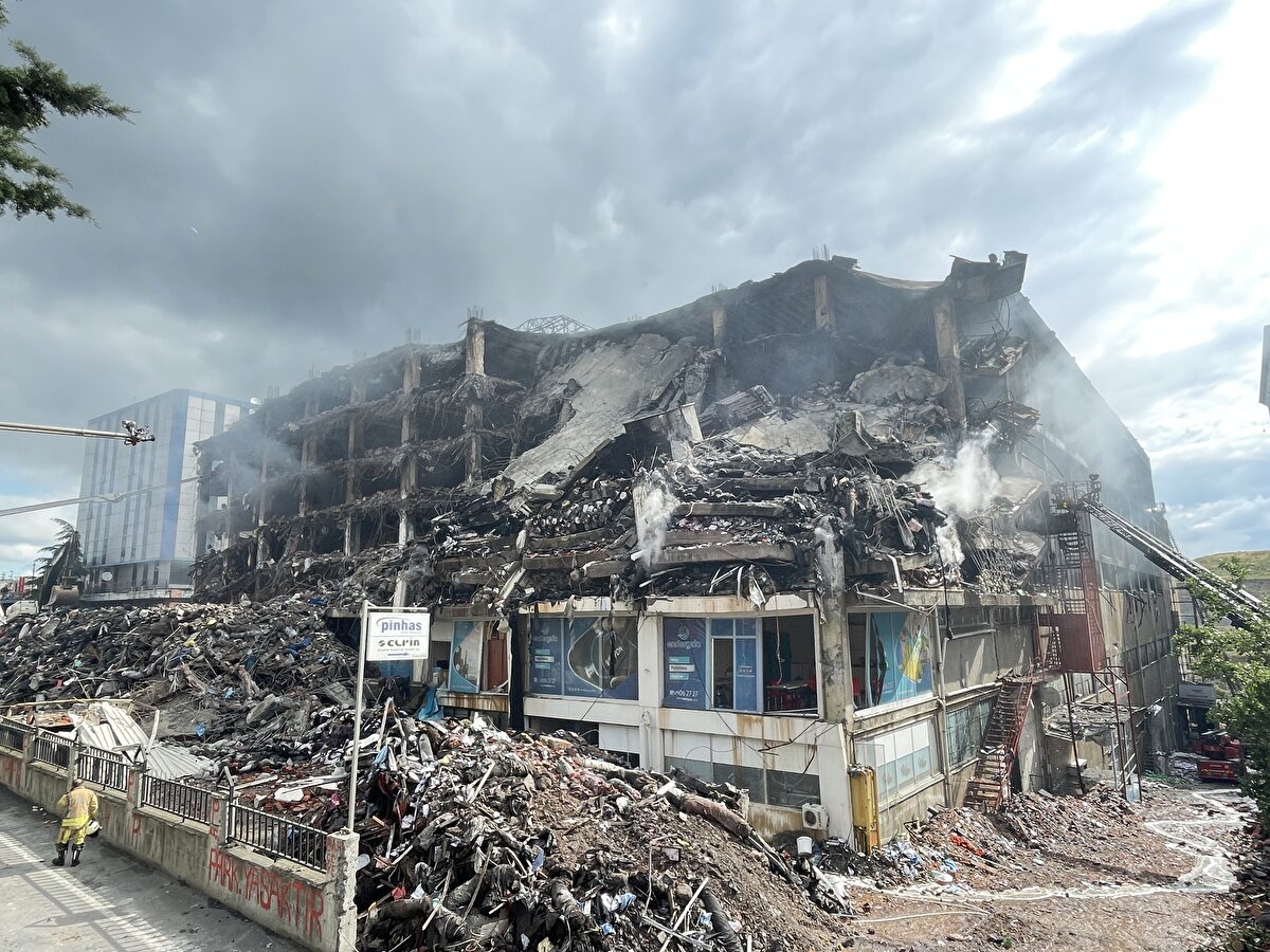 Dumanlar yükseliyor<br><br>Binanın üst katlarında başlayan ve tamamına sirayet eden yangını söndürme çalışmalarında 65 saate girildi.<br><br>Binanın caddeye bakan bölümünde iş makineleriyle en üst kattan zemine kadar devam eden yıkım çalışmaları tamamlandı. Moloz yığınlarının binanın ön tarafında büyük yer kapladığı görüldü.