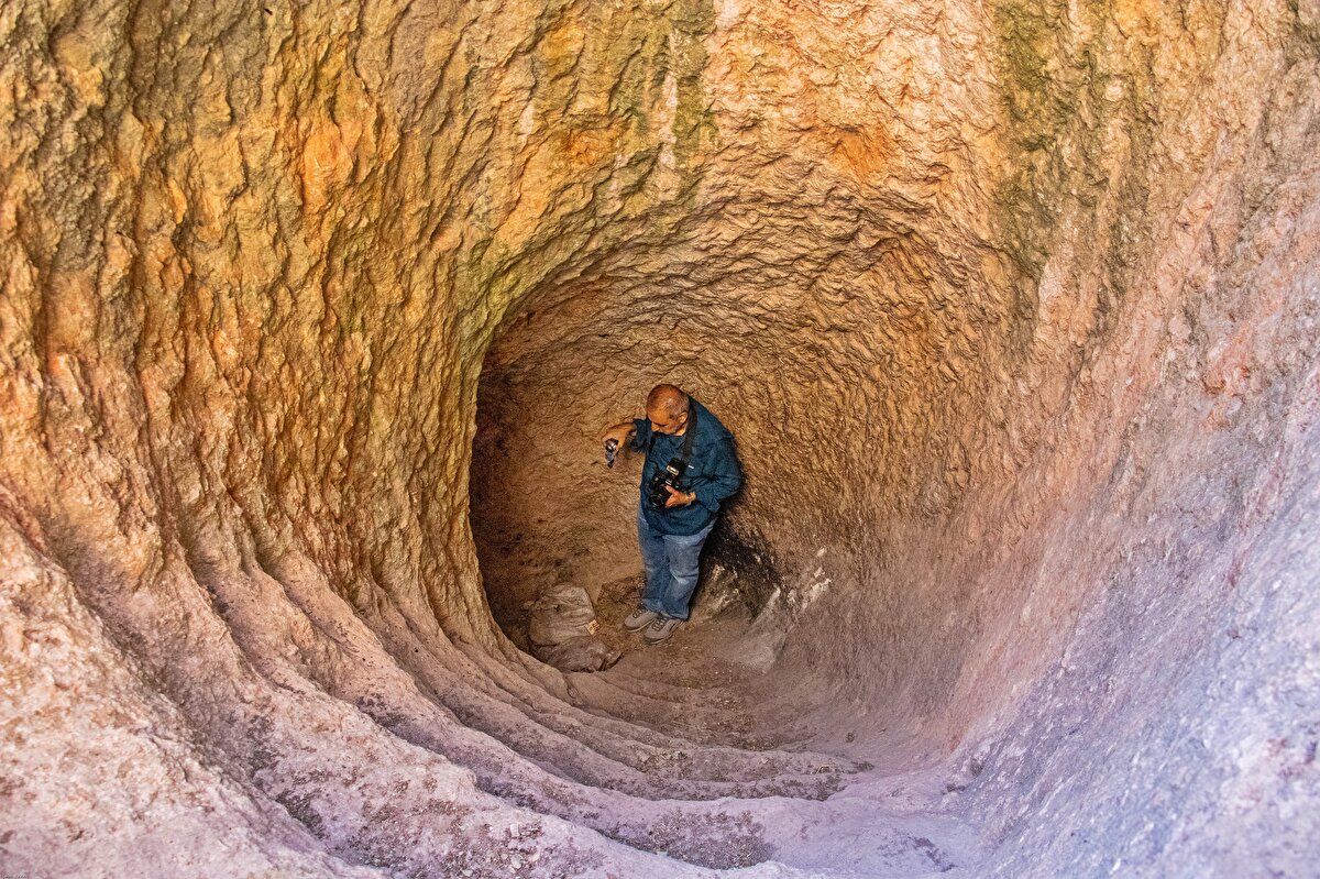 "PİRAMİT TARZI, 2 KATLI KAYA MEZARI VAR"<br>Kalede yöneticilere ait biri üç, diğeri bir kapasiteli 2 katlı 2 anıt mezarın da olduğunu belirten Prof. Dr. Yıldız, “Ayn Dar Kalesi'ndeki anıt kaya mezarı bölgede bulunan en ender kaya mezarlarından biridir. Piramit türü kaya mezarlarındandır. Bu tür kaya mezarları bu gölgede Asur ve Akat döneminde rastlıyoruz. Dicle ilçesinde, Eğil ilçesinde ve Hazro ilçesinde bu tür kaya mezarları var. Ama özellikle Ayn Dar Kalesi'ndeki kaya mezarı piramit şeklinde basamaklı yapılması bakımından diğerlerinde bir farklılık gösteriyor. Yine burada 2 katlı bir kaya mezarı odası görüyoruz. Alt katında içinde 3 platformu olan bir kaya mezar, hemen üst katta da ikinci bir kaya mezar odası var ve bu iki kaya mezar odasının üstü de kayanın yontulmasıyla piramit şeklinde anıt mezara dönüştürülmüştür. Tabii bu tür kaya mezarlarının özelliği şudur. Yani Genç Roma’ya kadar bölgede devam ediyor. Ölülerini, özellikle tabii, yöneticiler, önemli kişiler için yapılan kaya mezarlardır. Ölülerini o ölü platformu dediğimiz sekilere uzatırlar, kemik etten arındırıldıktan sonra, başka bir kişiyi ölünce ve oraya gömülmesi gerekiyorsa, o kemikler toplanılır kaya mezarı içerisinde bulunan kemik çukuruna gömülür ve bu sirkülasyon böylece devam eder” ifadelerini kullandı.