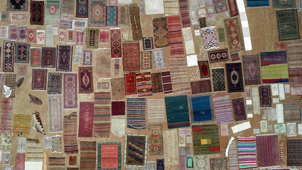 25 METREKARELİK HEREKE HALISI DOLARLA SATILDI<br>Kocaeli Hereke'de dokunan 60 yıllık yün halı da halı tarlasına güneşlenmesi için serildi. 25 metrekarelik halı 13 bin dolardan yurt dışındaki bir kişi tarafından alındı. Güneşlenme işlemi bittikten sonra halı, özel kargo ile sahibine gönderilecek. Havanın bugünlerde 45'li dereceleri gördüğü kentte halı güneşlendirme işleminin çalışanlar açısından zorlu olduğunu belirten Börekçi, "Her yıl olduğu gibi yine halı tarlasını faaliyete geçirdik. Halılarımız burada güneşlendirilip, daha sonra yıkanıp sahiplerine teslim edilecek. Bu işlemle hem halıya zarar veren bakteriler ve akarlar arındırılıyor hem de yün iplik güneşte kendi rengini buluyor. Daha canlı oluyor" dedi.<br>İlçenin farklı noktalarındaki halı tarlaları turizme de katkı sunuyor. Yerli ve yabancı fotoğraf meraklıları, halı tarlalarına gelerek, buralarda fotoğraf çekip, ilçe turizmine katkı sağlıyor.