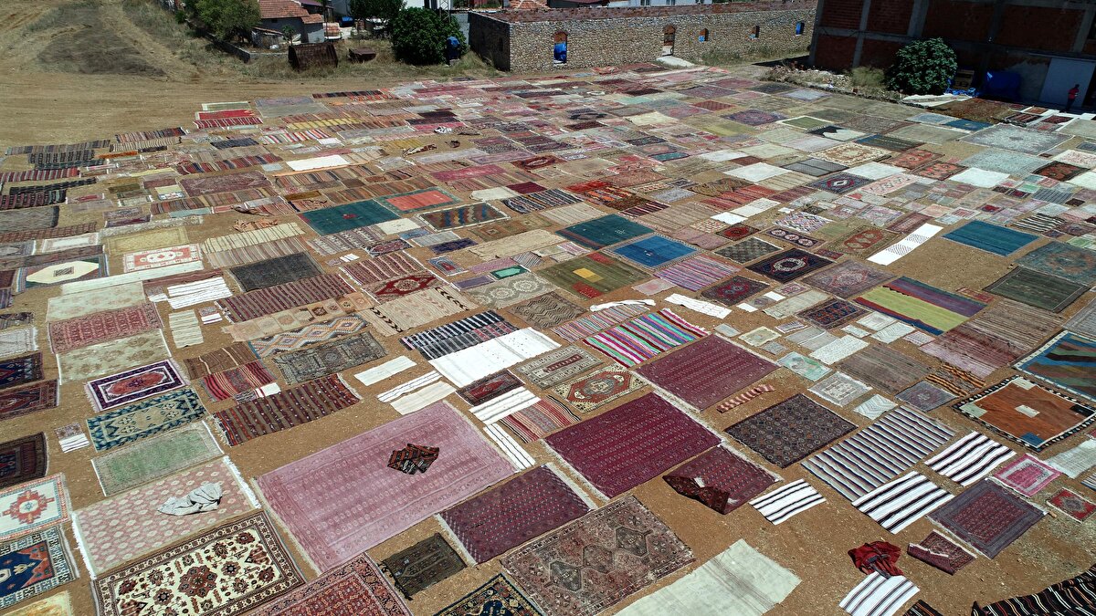 Döşemealtı ilçesinde yıllardır halı alım ve satışının yanı sıra onarımını da yapan Halil Börekçi, bu yıl buğday hasadının ardından 25 dönümlük tarlasına 2 bine yakın halı serdi.