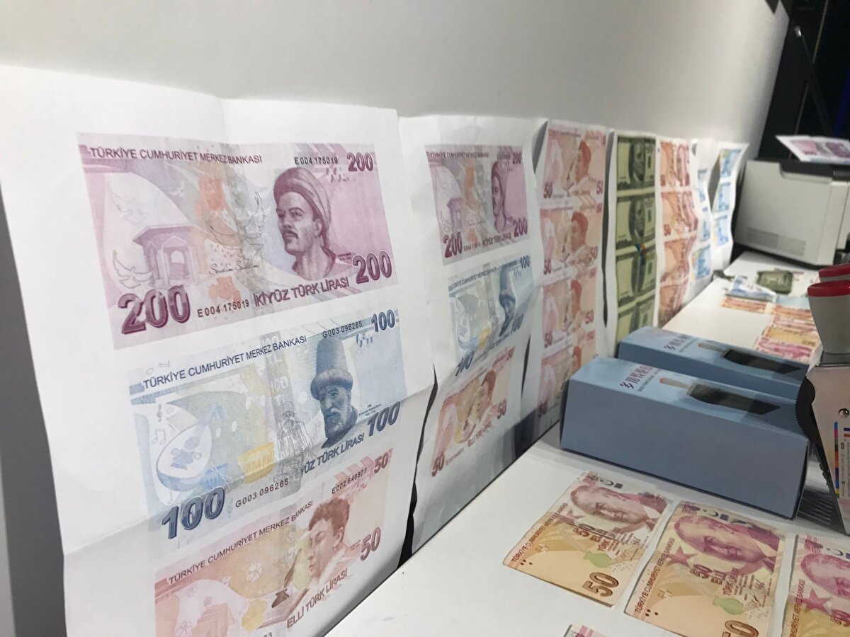  Şüphelinin üzerinde ve adresinde yapılan aramada 2 bin adet sahte 50 TL'lik banknot, 30 adet sahte 100 dolar, çok sayıda kesilmiş sahte para kağıtları, banka ve kredi kartları ile banka dekontları, sahte paraların basımında kullanılan; yazıcı, tarayıcı, boya, sıvı solüsyon, numaratör ve çok sayıda materyal ile basımı yapılmış sahte para kağıtları ele geçirildi.<br>