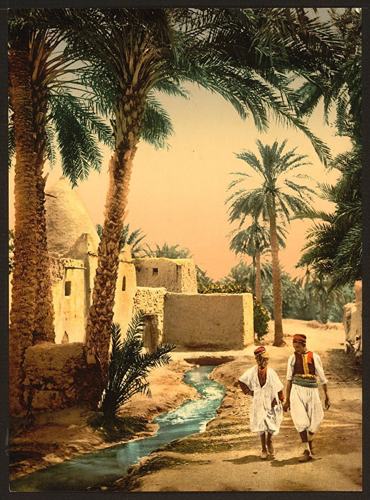 Tarihî şehirdeki bir sokakta yürüyen iki genç, Biskra.