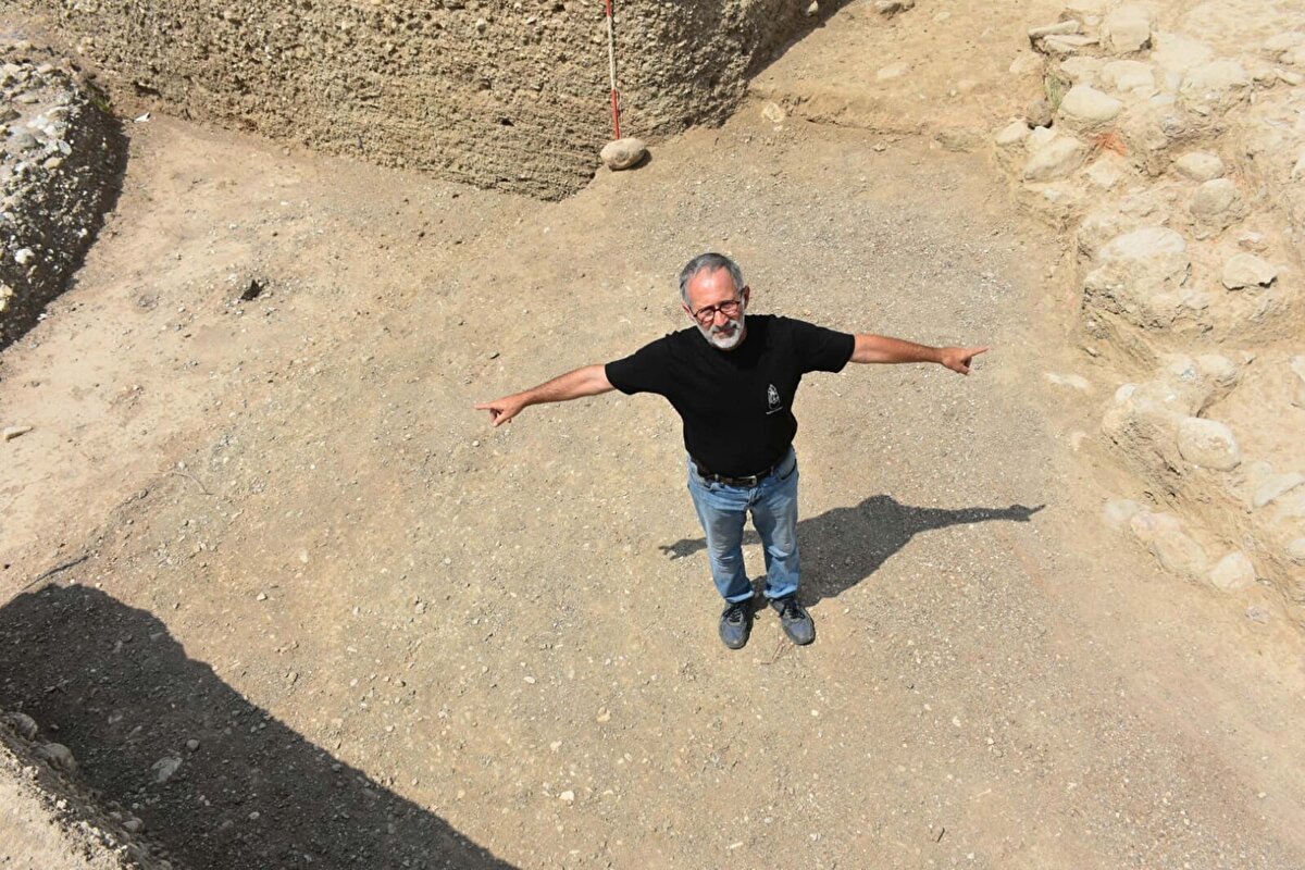 '4 KUŞAK BOYUNCA KULLANILMIŞ BİR YAPI'<br><br>Ege Üniversitesi Edebiyat Fakültesi Arkeoloji Bölümü Öğretim Üyesi ve Kazı Başkanı Doç. Dr. Zafer Derin, "İzmir'in ilk köy yerleşiminin olduğu Yeşilova Höyüğü'ndeyiz. Bu yılki kazılarda özellikle imarı nasıl kullanmışlar onu anlamaya çalıştık. Yerleşimin tam ortasından geçirilen 6,5 metre genişliğinde bir kanalın olduğunu gördük. İki tarafı, taşlarla döşenmiş. Toprakla set gibi yükseltilmiş. Günümüzden 8 bin 200 yıl önce; 4 kuşak boyunca kullanılmış bir yapı. Nitekim bu kanal zamanla dolunca, Roma döneminde aynı alan üzerinden künklerle su geçirilmeye devam edilmiş. Kanal 6,5 metre genişliğinde oldukça büyük. Yerleşim kanalın her iki tarafına inşa edilmiş. Su taşkınlarından etkilenmemiş yerleşim. Çünkü kanalın imarı ona göre yapılmış. 220 metre boyunca uzunluğunu tespit ettik. Bunun sadece küçük bir bölümünü açabildik. Çünkü kanalın içi çok yoğun bir şekilde çakıl taşlarıyla dolu" dedi.<br>