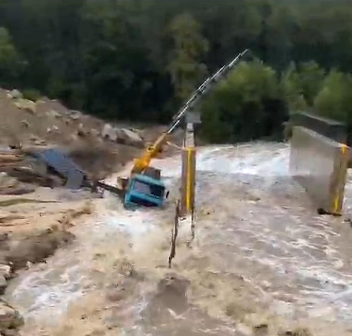 İŞ MAKİNESİ SELİN ORTASINDA KALDI<br>Bölgede yol ve köprü çalışması yapan kara yollarına bağlı bir iş makinesi akıntının ortasında kaldı. Suyun yükseldiğini gören operatör öncesinde araçtan çıkarak sele kapılmaktan kurtuldu.