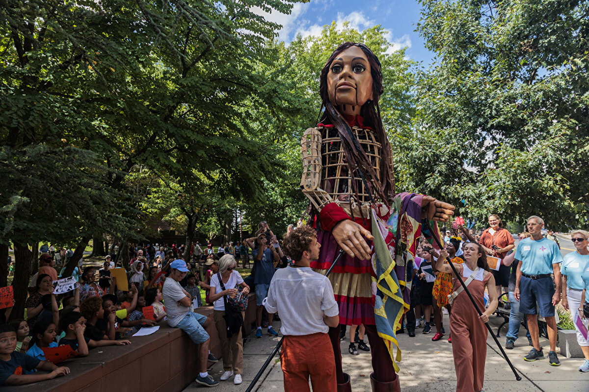 Suriyeli 9 yaşında bir mülteci kız çocuğu formundaki 3,5 metrelik dev kukla olan Küçük Emel yerlerinden edilmiş, çoğu ailesinden ayrı düşmüş tüm çocukları temsil etmektedir.