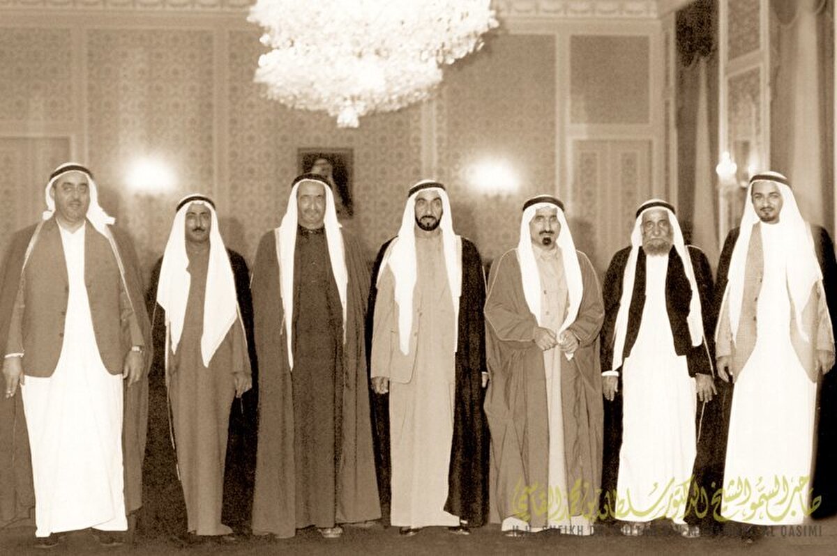 Birleşik Arap Emirlikleri Başkanı Şeyh Zayed bin Sultan el-Nahyan (ortada); Şeyh Muhammed bin Raşid el-Maktum, Dr. Şeyh Sultan bin Muhammad el-Kasımi, Şeyh Raşid bin Ahmed el-Mualla, Şeyh Sakr bin Muhammad el-Kasımi, Şeyh Muhammed bin Hamad el-Şarki ve Şeyh Humaid bin Raşid el-Nuaimi ile birlikte Ra’s el-Hayme'nin Birleşik Arap Emirlikleri Birliği'ne katılmasının ardından yedi BAE federasyonu üyesi devletinin yöneticileriyle birlikte poz veriyor, Abu Dabi Başkanlık Sarayı, 10 Şubat 1972.