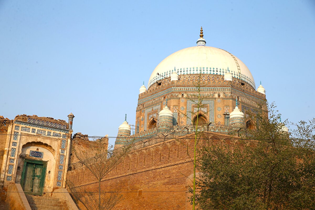Kırmızı kum taşından inşa edilen türbede ahşap oymalı paneller, oymalı ve renkli tuğlalarla oluşturulan desenler göze çarpıyor.