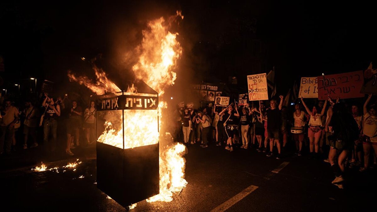 İsrail bayrakları ile Başbakan Netanyahu ve hükümetindeki siyasetçiler aleyhinde pankart, afiş ve dövizler taşıyan protestocular, erken seçim çağrısı yaptı ve alanda büyük bir ateş yaktı.<br>