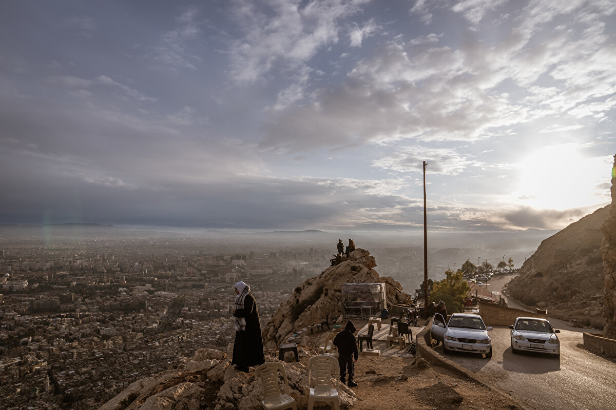Suriyeli genç, "Arkadaşlarıma hep, 'Bizler büyük bir hapishanede yaşıyoruz.' derdim. Sednaya, işkence merkezleri var. (Şam'ı göstererek) Bu da büyük hapishaneydi, kentin tüm halkı koca hapishanede yaşıyordu. Birçok şeyden mahrumdu." diye konuşuyor.