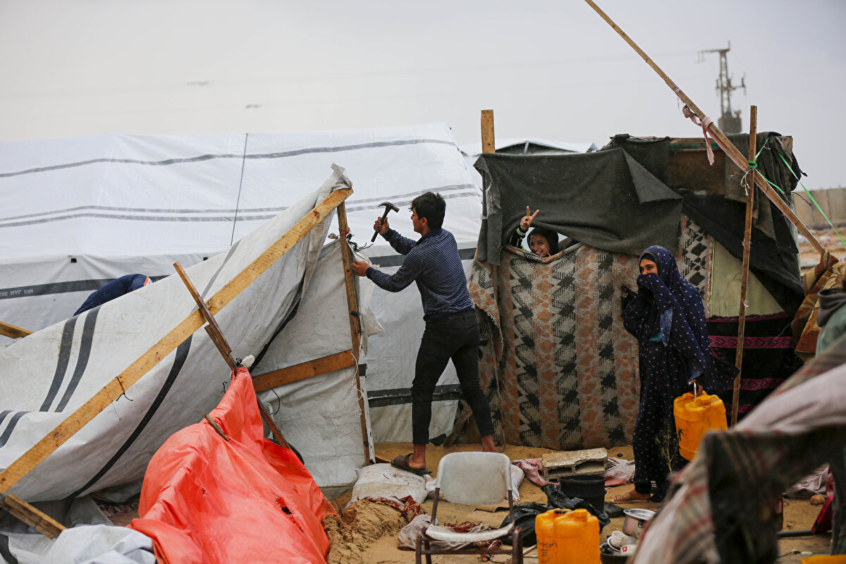 Gazze Şeridi'nin güneyindeki deniz kıyısında, gece saatlerinde şiddetli fırtına nedeniyle parçalanan ve büyük bölümünün uçup giden çadırının kalıntılarını toplayan Ebu Cemal Halife, İsrail'in 7 Ekim 2023'te başlayan saldırıları nedeniyle 10 kez yerinden edildiklerini söyledi.