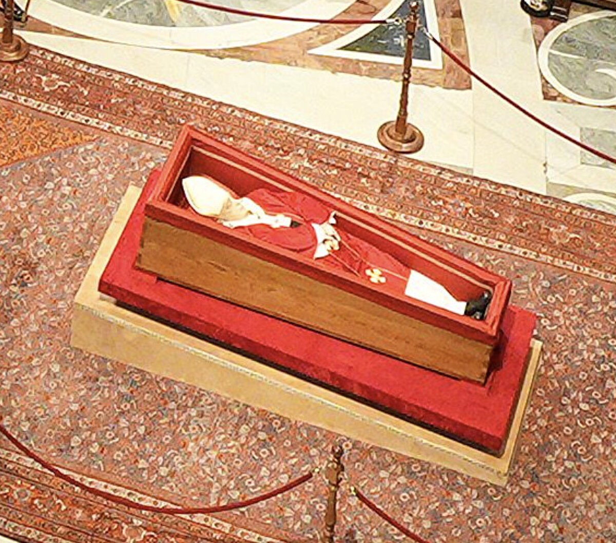 Kırmızı giysiler ve sembollerle donatıldı<br><br>Papa Francis’in naaşı, beyaz iç giysilerin üzerine kırmızı Bizans gelenekli cenaze giysileriyle örtüldü. Başında piskoposlara özgü beyaz ve altın detaylı mitrası, elinde ise Katoliklerce dua etmekte kullanılan bir tesbih bulunuyor.<br><br>Ayrıca, kendisine ait olan sade gümüş yüzüğünü takıyor. Geleneksel olarak her papa için özel olarak basılan “Balıkçının Yüzüğü” ölümü sonrası imha ediliyor. Omzunda ise, siyah haçlarla süslenmiş beyaz yünlü pallium bulunuyor; bu, papalığın en önemli sembollerinden biri.