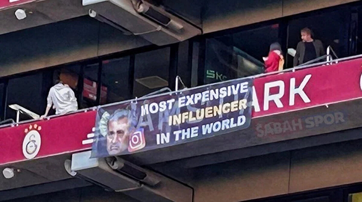 Bir diğer fotoğrafta ise <br>Mourinho'nun fotoğrafının yer aldığı pankartta "Dünyanın en pahalı influencer'ı (Most expensive influencer in the world)" cümlesine yer verildi.<br>