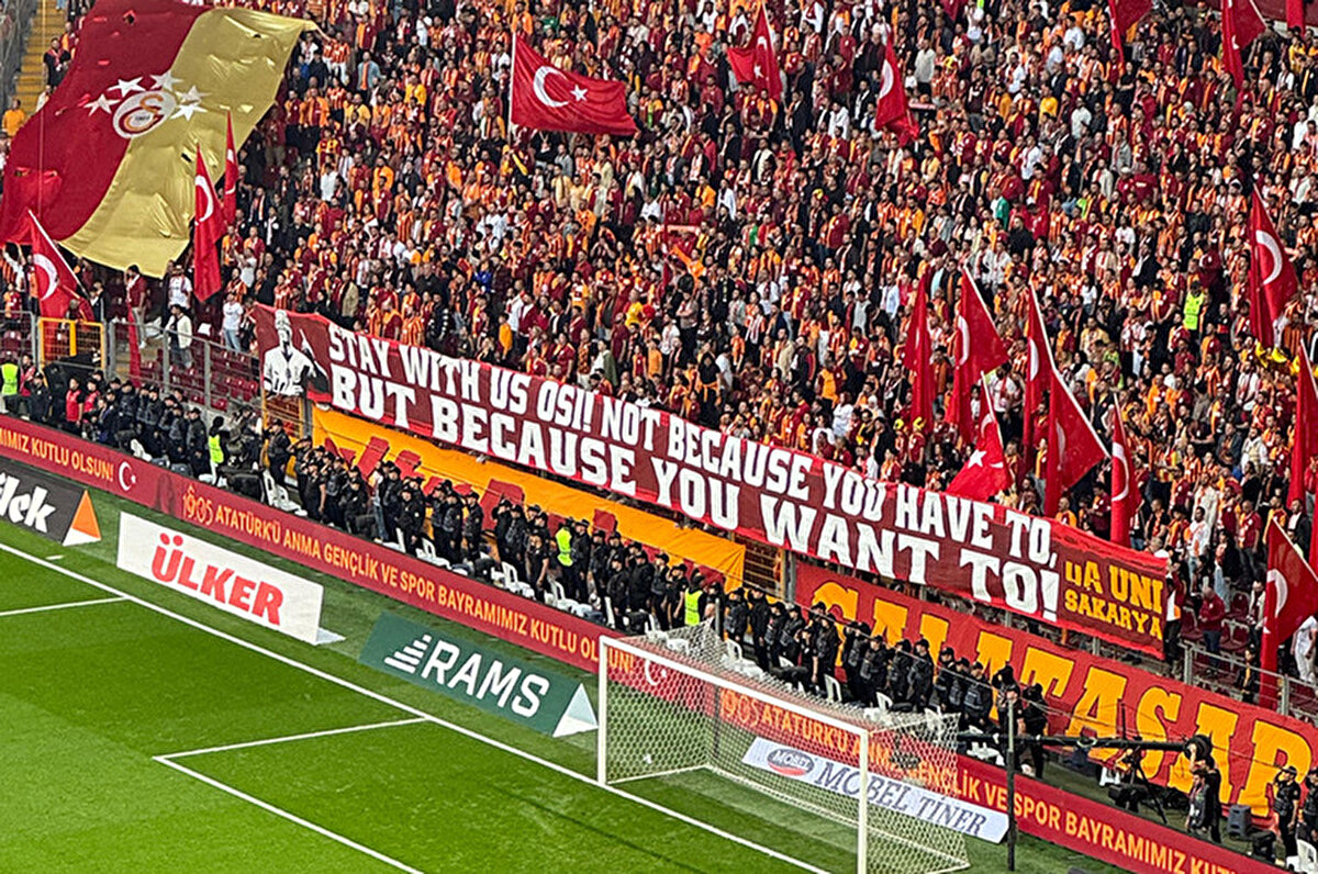 Müsabaka öncesinde ise kuzey tribününde "Zorunda olduğun için değil, istediğin için bizimle kal Osi" yazılı pankart açıldı.<br>