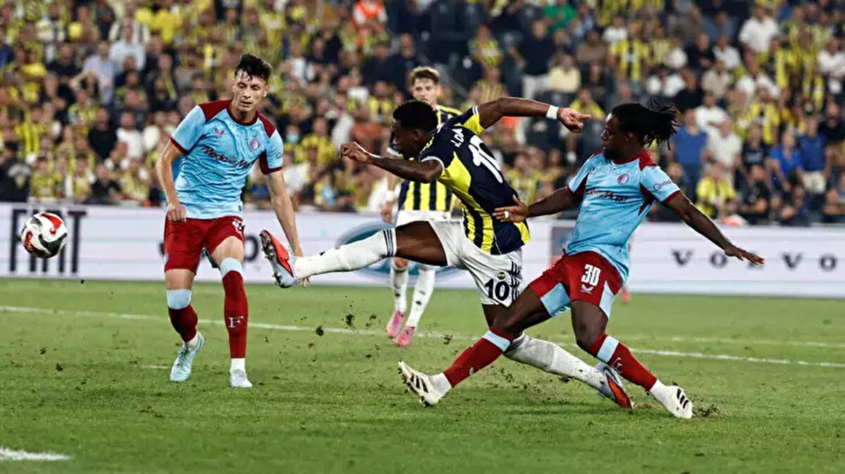 Fenerbahçe UEFA Şampiyonlar Ligi Play-Off Turunda Benfica Karşısında<br><br>Fenerbahçe, UEFA Şampiyonlar Ligi'ne bu sezon 3. ön eleme turundan başladı ve Hollanda ekibi Feyenoord'u elemeyi başardı. Deplasmandaki ilk maçta 2-1 mağlup olan sarı-lacivertliler, sahasında 5-2'lik skorla galip gelerek adını play-off turuna yazdırdı. Fenerbahçe, UEFA Şampiyonlar Ligi play-off turunda bu akşam İstanbul’da Benfica ile karşı karşıya gelecek. Sarı-lacivertliler, sakatlığı bulunan Cenk Tosun’u kadrodan çıkarırken, yerine Cengiz Ünder’i UEFA listesine dahil etti. Fenerbahçe’nin UEFA kadrosunda İrfan Can Eğribayat, Dominik Livakovic, Çağlar Söyüncü, Milan Skriniar, Talisca ve Youssef En-Nesyri gibi isimler yer alıyor.