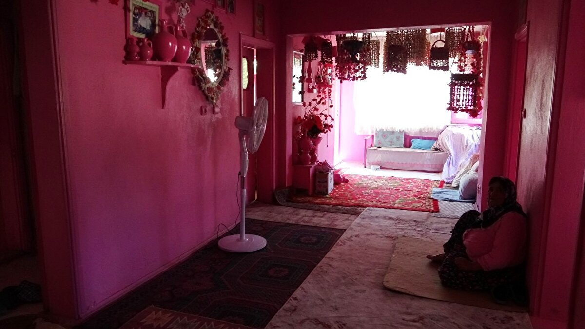 Isparta’da yaşayan 75 yaşındaki Sakine Akkul, çocukluğundan beri sevdiği pembe renkle boyadığı eviyle tanınıyor. Geçtiğimiz yıllarda hakkında yapılan haberlerin ardından kendisine "nazar değdiğine" inanan Akkul, artan sağlık sorunları nedeniyle yürüyemez hale geldiğini, kişisel ihtiyaçlarını karşılayamadığını ve birlikte yaşadığı oğluna yük olduğunu belirterek akülü engelli sandalyesi istiyor.<br><br>Isparta’nın merkeze bağlı Sav beldesinde yaşayan 75 yaşındaki Sakine Akkul, bulduğu her şeyi pembeye boyuyor. Yaşadığı evin her detayını pembeye boyayan Sakine teyze, pembe eviyle dikkat çekiyor. Tek katlı evinin dış kapısından duvarlarına, evin içerisinde bulunan süs eşyalarına kadar pembeye boyayan Akkul, pembe aşkının küçük yaşlarda başladığını söyledi.