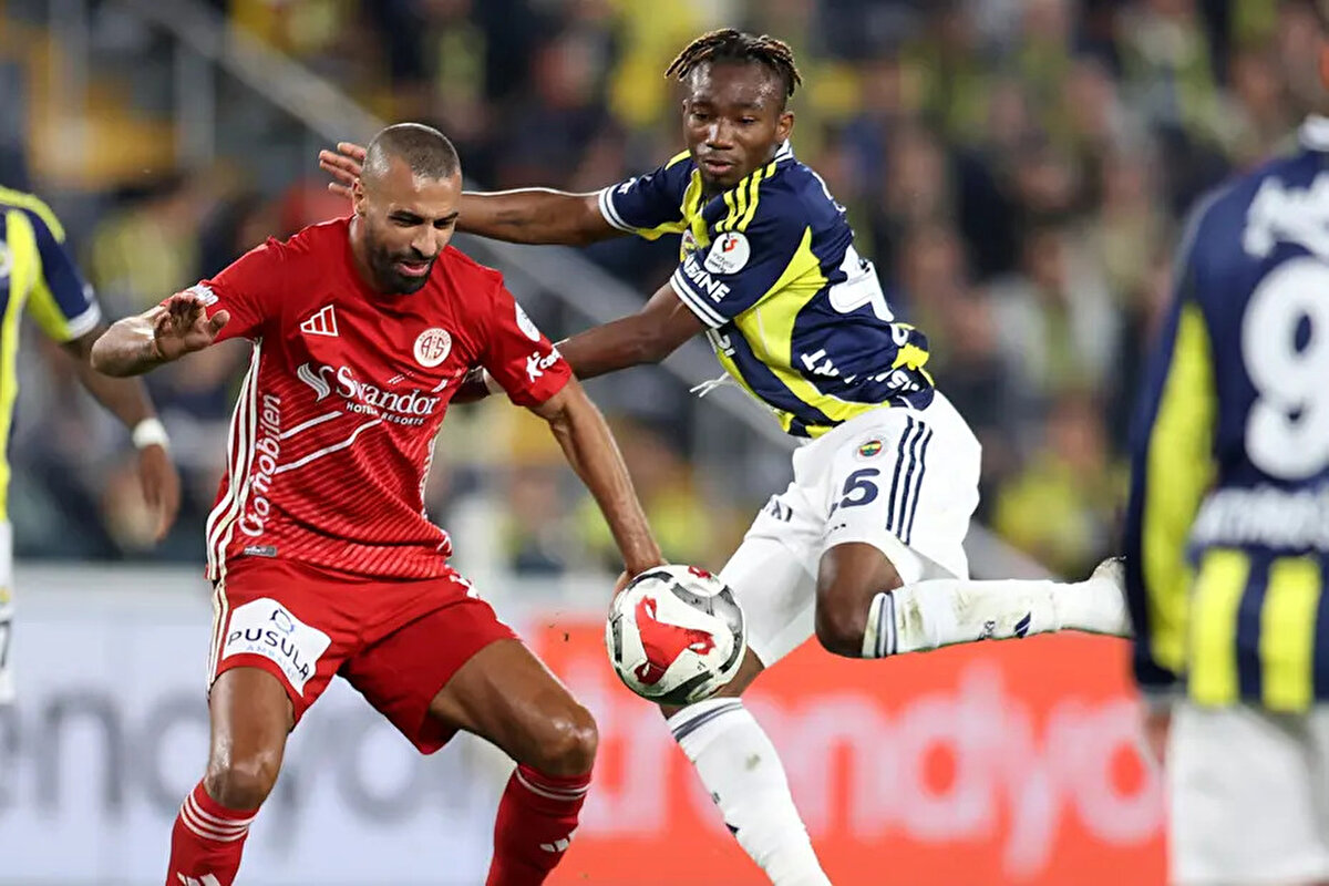 Fenerbahçe'nin elle oynama beklediği pozisyonda devam kararı doğru mu?<br><br>Deniz Çoban: Hocam ben bunun elle oynama olduğunu düşünüyorum. Açılar çok yeterli değil çünkü çok ölü bir noktada. Oyuncu top gelirken kolunu hazırlayıp vücudunu da sağa doğru yatırarak kolunu kaçırmayı denemek yerine o kolun genişliğinin avantajını kullanarak topu önüne almış. Bence burada -ceza sahasının dışında görünüyor pozisyon- bir elle oynama var. Hakemin bunu değerlendirmesi gerekirdi diye düşünüyorum. Bu top 11 metreden değil de 2 metreden geliyor olsaydı o zaman elini kaçıracak kadar vakti yok, refleks derdim.<br><br>Bahattin Duran: Hocam bence de pozisyon ceza sahasının dışında. Top ele geldiği anda oyuncunun sağ ayağı ceza sahasının dışında. O kol sağ ayakla aynı hizada olsa bile ceza sahasının dışında. El ve kol vücuda doğal konumda ancak Deniz Çoban'ın da ifade ettiği gibi kolunu genişletmiyor, vücuduyla birlikte kolunu genişletmiş oluyor. Yani kolu, vücuduna göre yine doğal ama vücudunu genişletti. Bu pozisyon benim için bir elle oynama. Serbest vuruşla cezalandırılmalıydı.<br><br>Bülent Yıldırım: İlave söyleyeceğim tek şey; sağ ayak ve kolun temas noktası ceza alanının dışında. Ben de toparlanacak mesafesi olduğu için kolunu genişleterek o alana yattığını düşünüyorum.