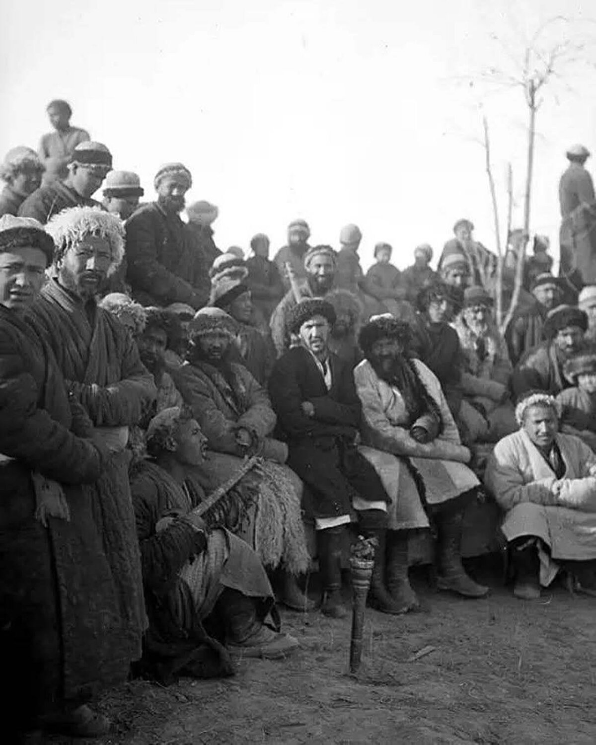Şarkı söyleyen bir kişinin etrafında toplanan Uygurlar. Yarkent, 1927-1928.